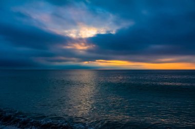 Deniz üzerinde dramatik bulutlarla gün doğumu