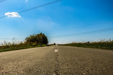 Mavi gökyüzü ve beyaz bulutlu boş asfalt yol