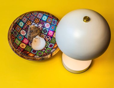 Bir fincan kahve, bir fincan çay tabağı, sarı bir masa ve bir lamba.