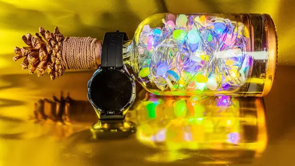 Ahşap bir masanın arka planında cam kavanozlarda yılbaşı süsleri ve ışıklar.