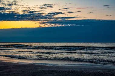 Denizde gün doğumu, dalgalar ve bulutlar