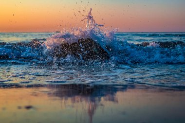 Denizde gün batımı. Dalga sıçrıyor ve sıçrıyor.