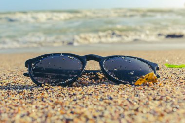 Kumsalda güneş gözlüğü ve kumsalda deniz. seyahat kavramı.