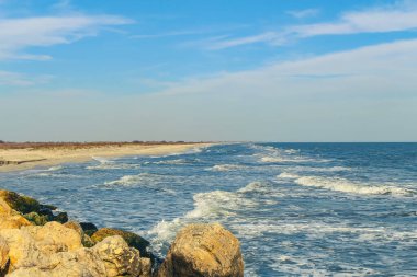 Dalgalar ve mavi gökyüzü ile deniz kıyısı.
