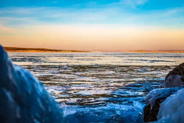 Kışın donmuş nehir ve buz. Akşamları Baykal Gölü kıyısında buz
