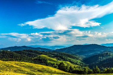 Mavi gökyüzü ve ormanlı yeşil dağlar