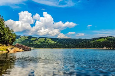 Güzel bir göl, mavi bir gökyüzü ve yazın arka planda küçük bir tekne.