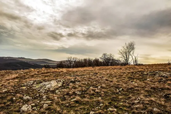 Bir dağ manzarası ve arka planda bulutlu bir gökyüzü.
