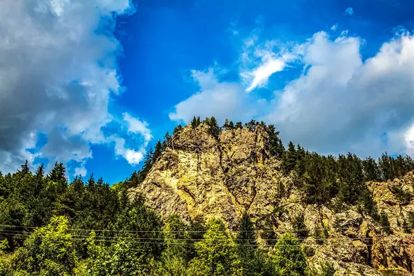 Bulutlu gökyüzü ile kayalık bir dağın güzel bir görüntüsü.