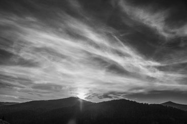 Bulutlu gökyüzü olan bir dağ manzarasının siyah ve beyaz fotoğrafı