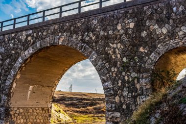 Güneş ışığında dağlarda eski bir köprünün yakın çekim görüntüsü.