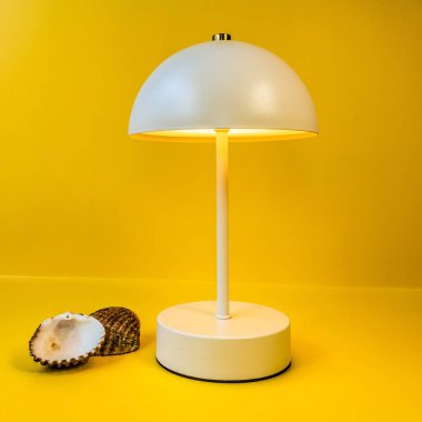 Sarı arka planda lamba ve sarı kabuklu beyaz ve siyah yuvarlak masa..