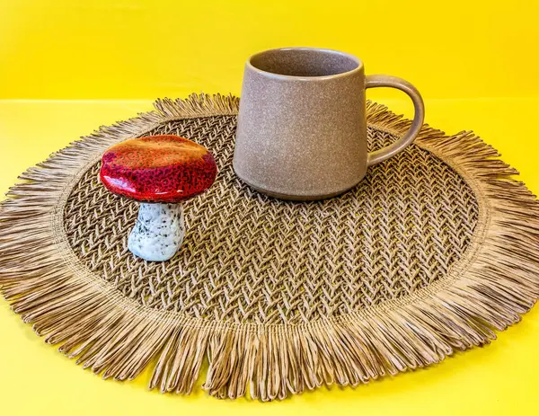 Bir fincan çay ve masasında hasır şapka olan kırmızı bir eşarp ile tabağın dikey görüntüsü.