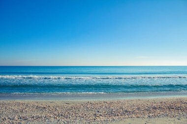 Sakin bir yaz akşamında mavi gökyüzü ve beyaz bulutlarla güzel bir deniz manzarası.