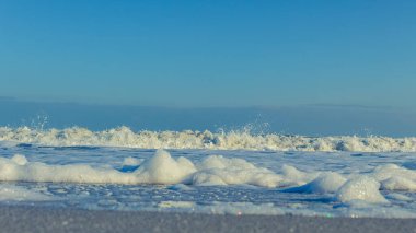 Kışın kumlu sahilde deniz köpüğü