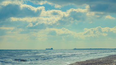 Dalgalar ve bulutlarla dolu güzel bir sahil.