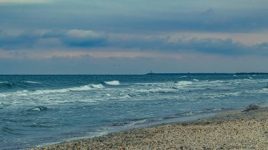 Arka planda fırtınalı bir gökyüzü olan kumlu bir sahilin dikey görüntüsü.