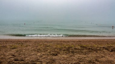 Deniz sisle kaplı ve kumsalın dalgaları.