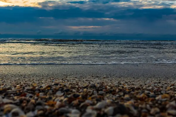 Deniz kıyısı, gün batımı ve bulutlu gökyüzü
