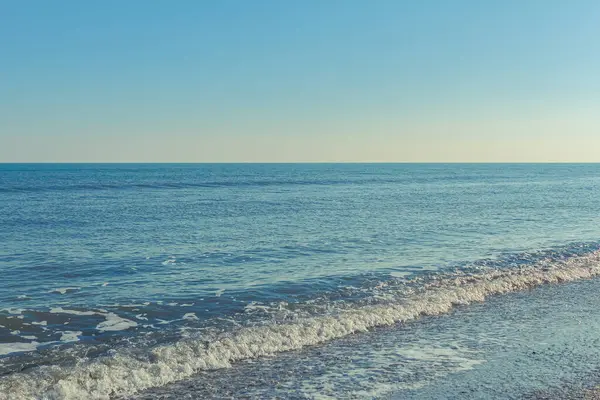 Yaz zamanı kumlu sahilde deniz dalgaları.