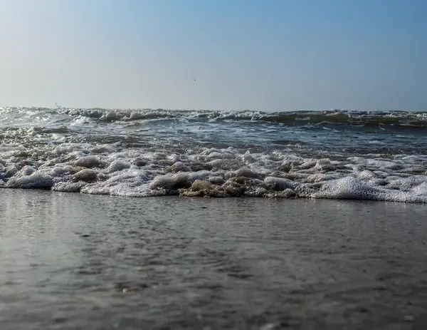 Kumsalda deniz dalgaları ve köpük