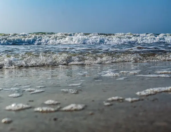 Beyaz kumlu güzel deniz manzarası ve kumsalda dalgalar ve bulutlarla mavi gökyüzü.