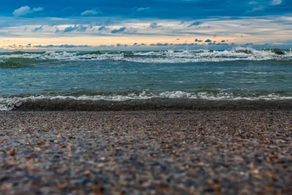 Kumlu bir sahilde deniz dalgaları ve köpük.