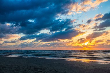 Baltık deniz plajı, akşam gökyüzü ve güneş ışığı, kum tepesi. Parlayan dalgalar, günbatımı, Letonya, Avrupa.