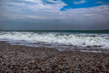 Kara sahilde dalgalar ve köpüklerle dolu bir sahil.