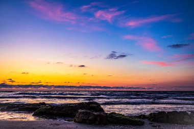 Denizde renkli bir gün batımı Sahilde küçük dalgalar
