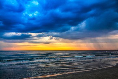 Deniz kıyısında gün batımında dramatik bir gökyüzü.