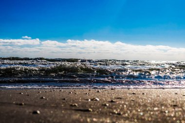 Mavi gökyüzünde deniz dalgaları.