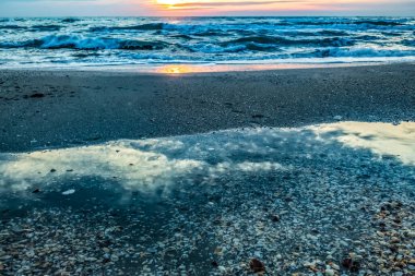 Sahilde gün batımı Denizde bir sürü bulutla