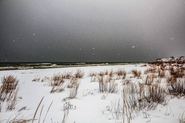 Kış akşamında karla kaplı plaj.