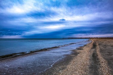 Bulutlu gökyüzü ile kumlu bir sahilin güzel bir görüntüsü.