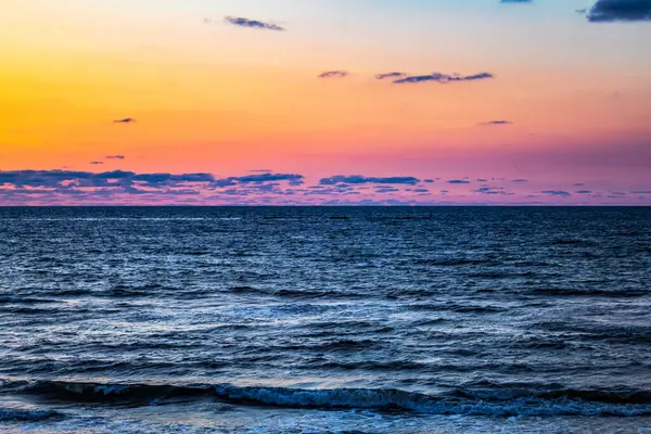 Denizde gün batımı, bulutlu renkli gökyüzü, akşam vakti kumsalda güzel bir gün batımı.