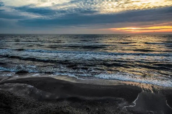 Denizde gün batımı. Sahilde gün batımı. Denizin dalgaları