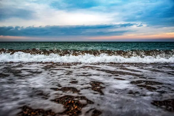 Dalgalar ve bulutlarla dolu güzel bir sahil.
