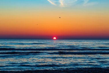Büyük bir güneşle denizin üzerinde güzel bir gün doğumu.