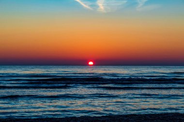 Büyük bir dalgayla deniz sahilinde gün batımı