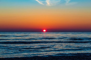 Sahilde gün batımı. deniz, dalgalar, bulutlar.