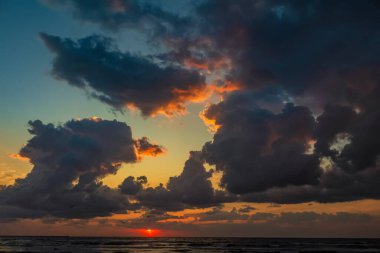 Denizde renkli bir gün batımı dramatik bulutlar ve dramatik gökyüzü ön planda..