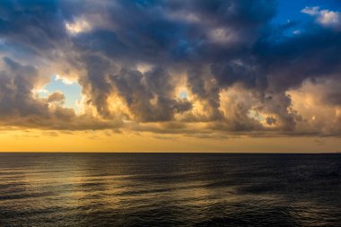 Bulutlu dramatik günbatımı gökyüzü ve koyu mavi deniz