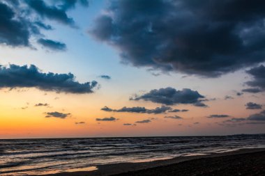 Deniz kıyısında dramatik bulutlarla gün batımı