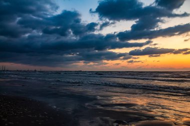 Sahilde bulutlar ve gökyüzüyle dramatik bir gün batımı