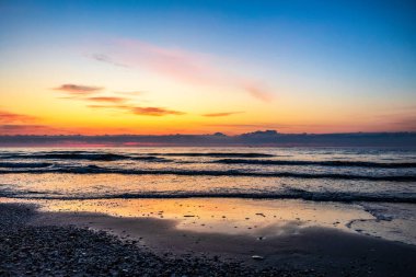 Büyük bir dalgayla denizin üzerinde güzel bir gün doğumu.