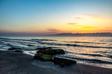 Yazın gün batımı güzel bir plajla denizde.