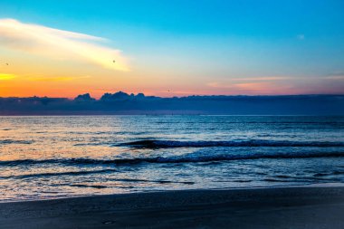 Sahilde gün batımı Renkli bir gökyüzü ve bulutlarla