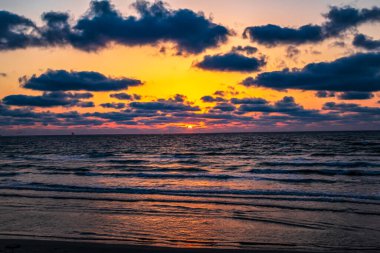 Güzel deniz ve bulutlarla kumsalda gün batımı