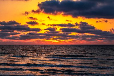 Denizin üzerinde renkli bir gün batımı. Bulutlu dramatik gökyüzü
